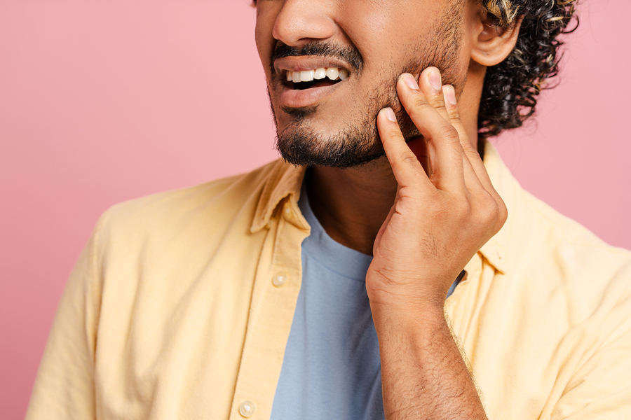 Person holding their jaw in pain.
