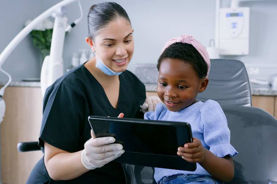 Dental assistant talking to child at the dentist.