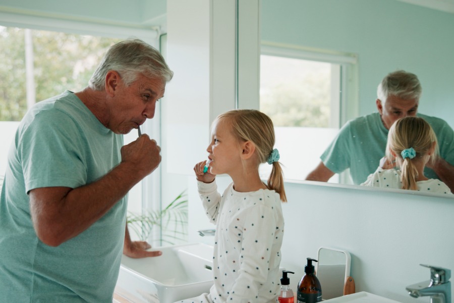 older man and granddaughter brushing their teeth