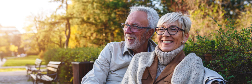 older couple sitting on bench in fall